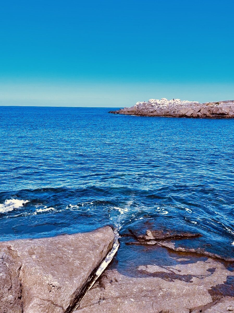 rocky shoreline and blue water at Nubble Lighthouse York Maine